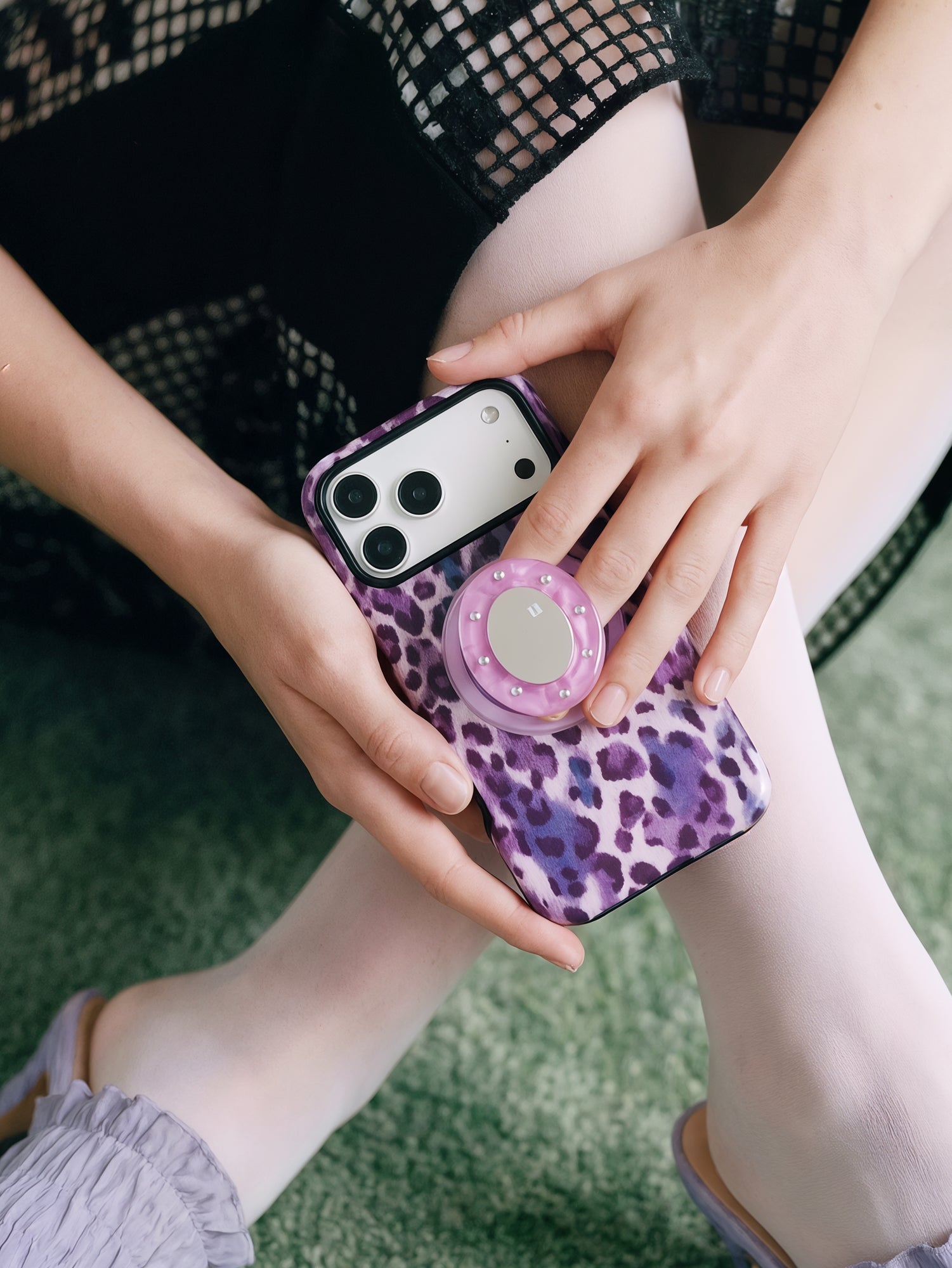 Hand holding the violet leopard phone case with fingers around the retractable MagSafe pop-grip