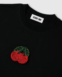 Detail of the cherry motif bead-woven from hundreds of red and green glass seed beads in raised concentric rows on cotton