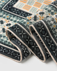Edge detail of the mosaic silk scarf showing the tile-floret border on charcoal and cream margin