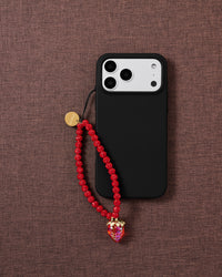 Red sparkle bead phone strap with strawberry charm worn hands-free from the wrist