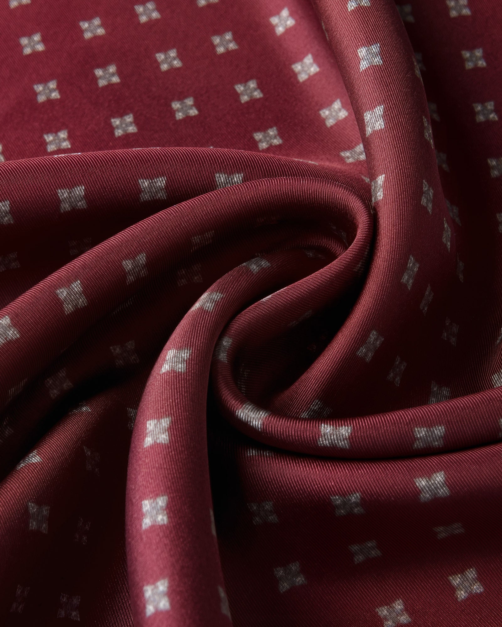 Close-up of the burgundy silk swirled to show the silver floret motif and the soft drape