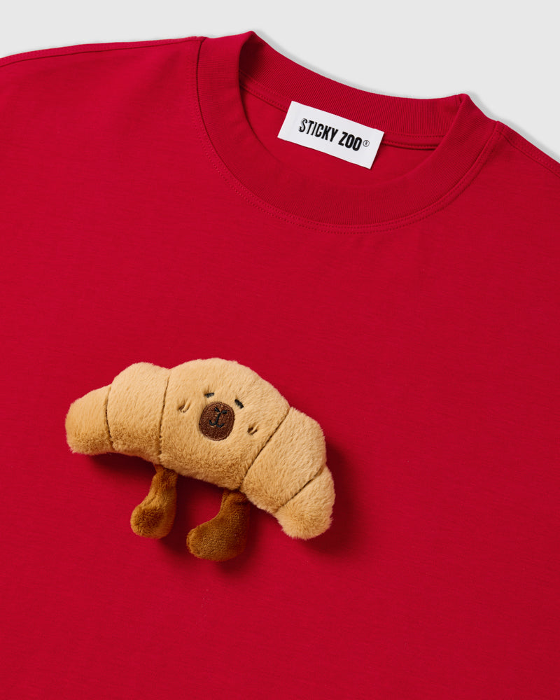 Close-up of neckline on STICKYZOO red Runaway Croissant T-Shirt showing plush croissant and brand label