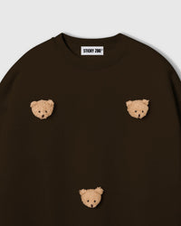 Detail of scattered plush teddy bear faces on STICKYZOO brown sweatshirt showing handmade craft