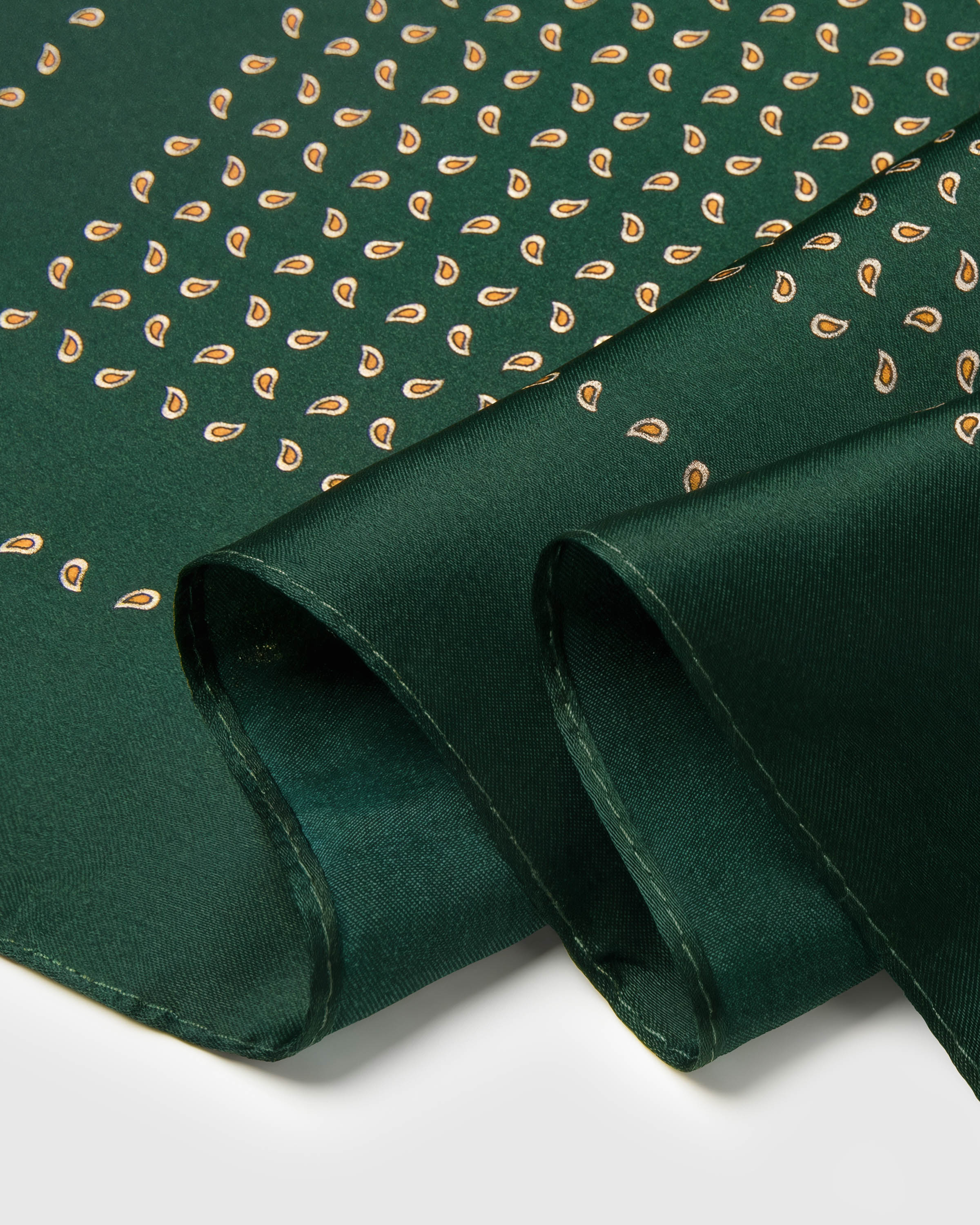 Close-up of the hand-illustrated gold droplet paisley printed in archival inks on emerald silk