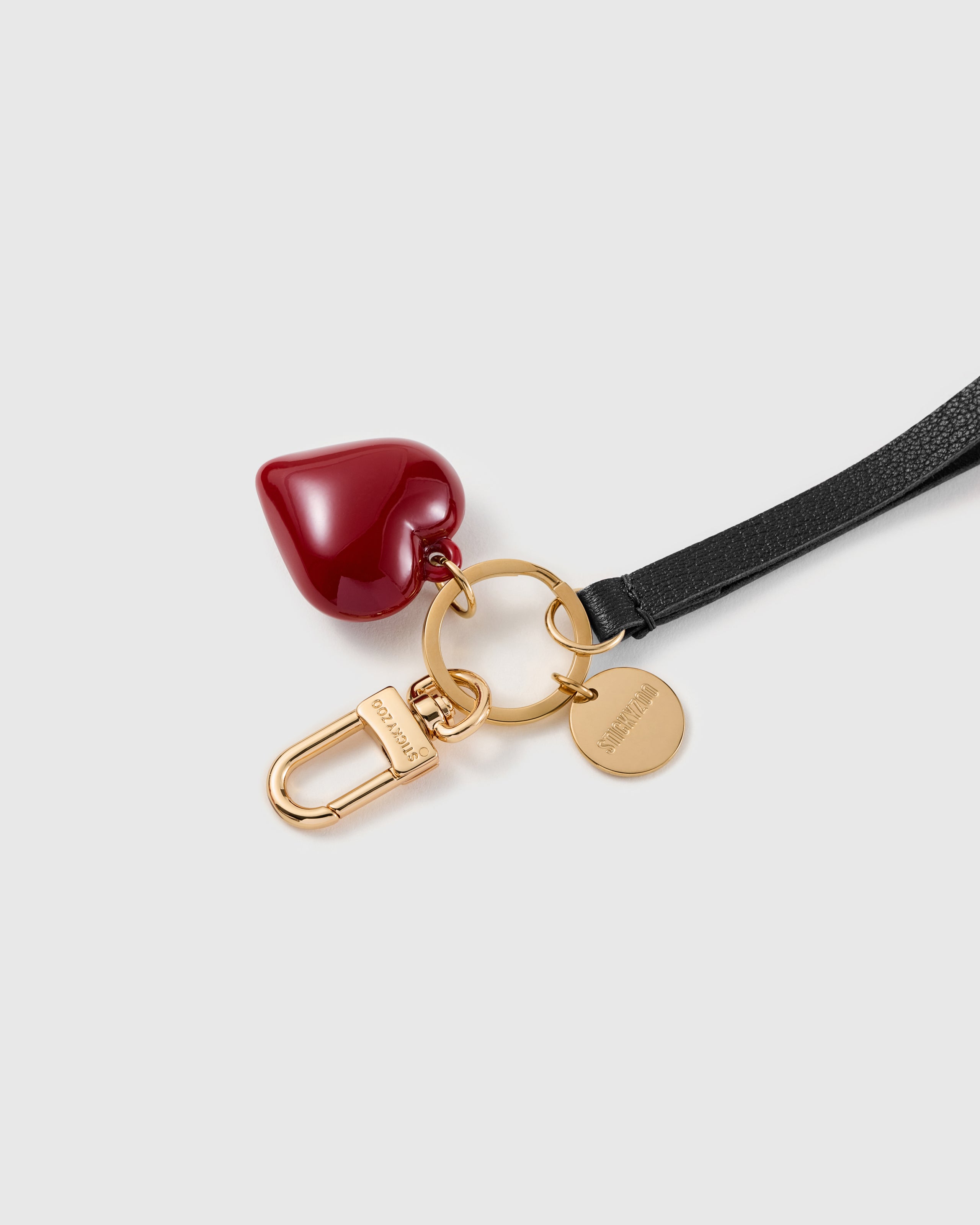 Glossy crimson molded heart charm, black textured wristlet and 18K gold-plated clasp with engraved STICKYZOO disc