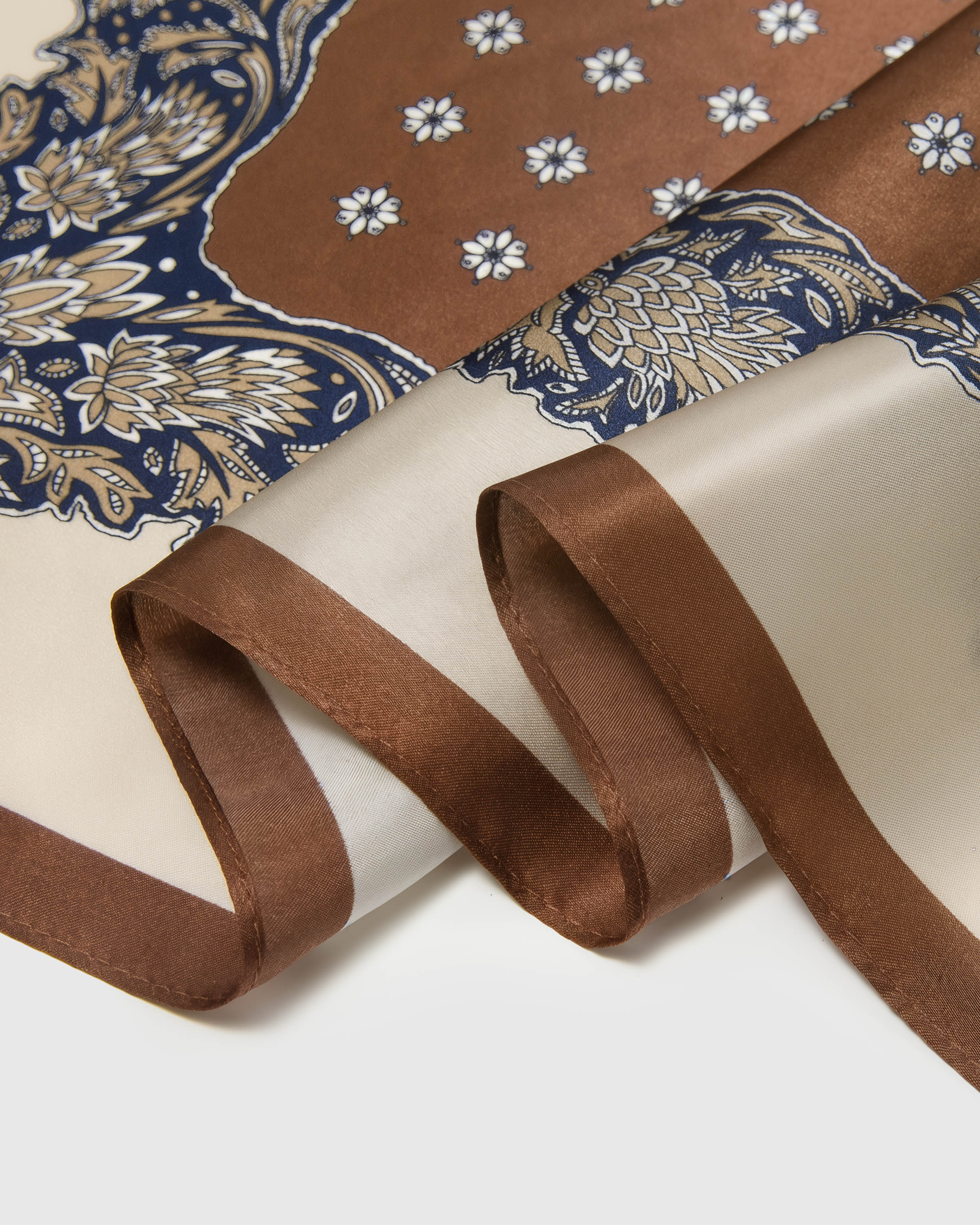 Close-up of the chestnut outer edge, ivory band and baroque paisley border on pure silk