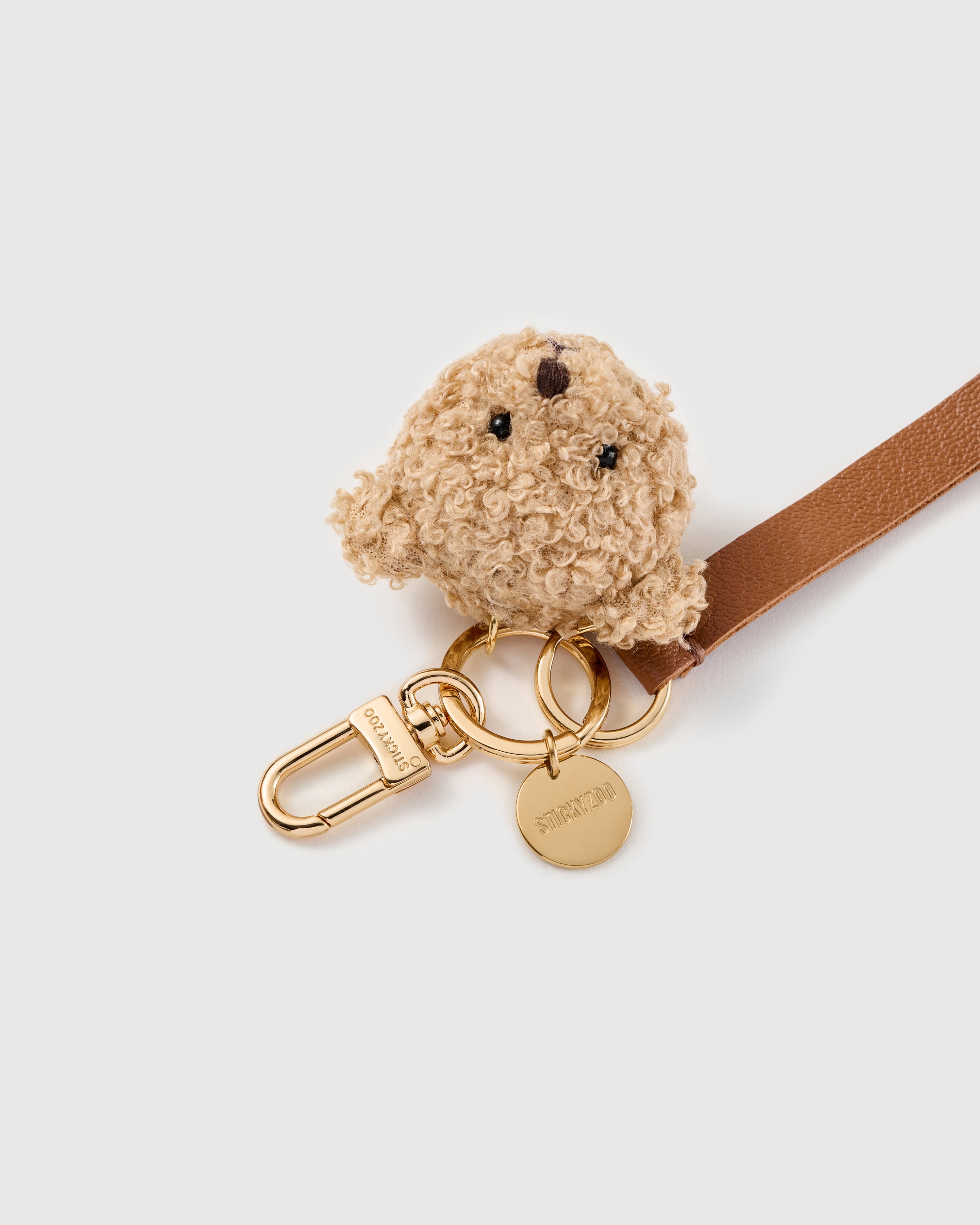 Tiny bear face leather phone strap clipped to a phone case showing the hands-free wrist loop in use