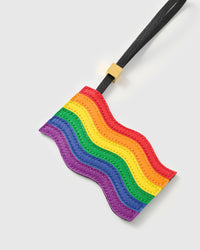 Close-up of handmade pride rainbow flag charm showing hand-cut leather layers and waving silhouette