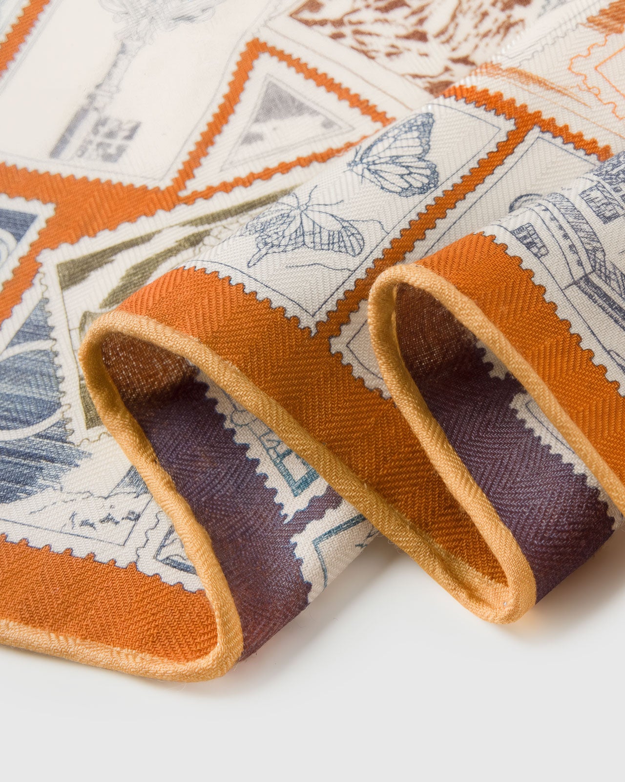 Close-up of the terracotta silk border showing the cream field and slate-blue stamp illustrations on pure silk