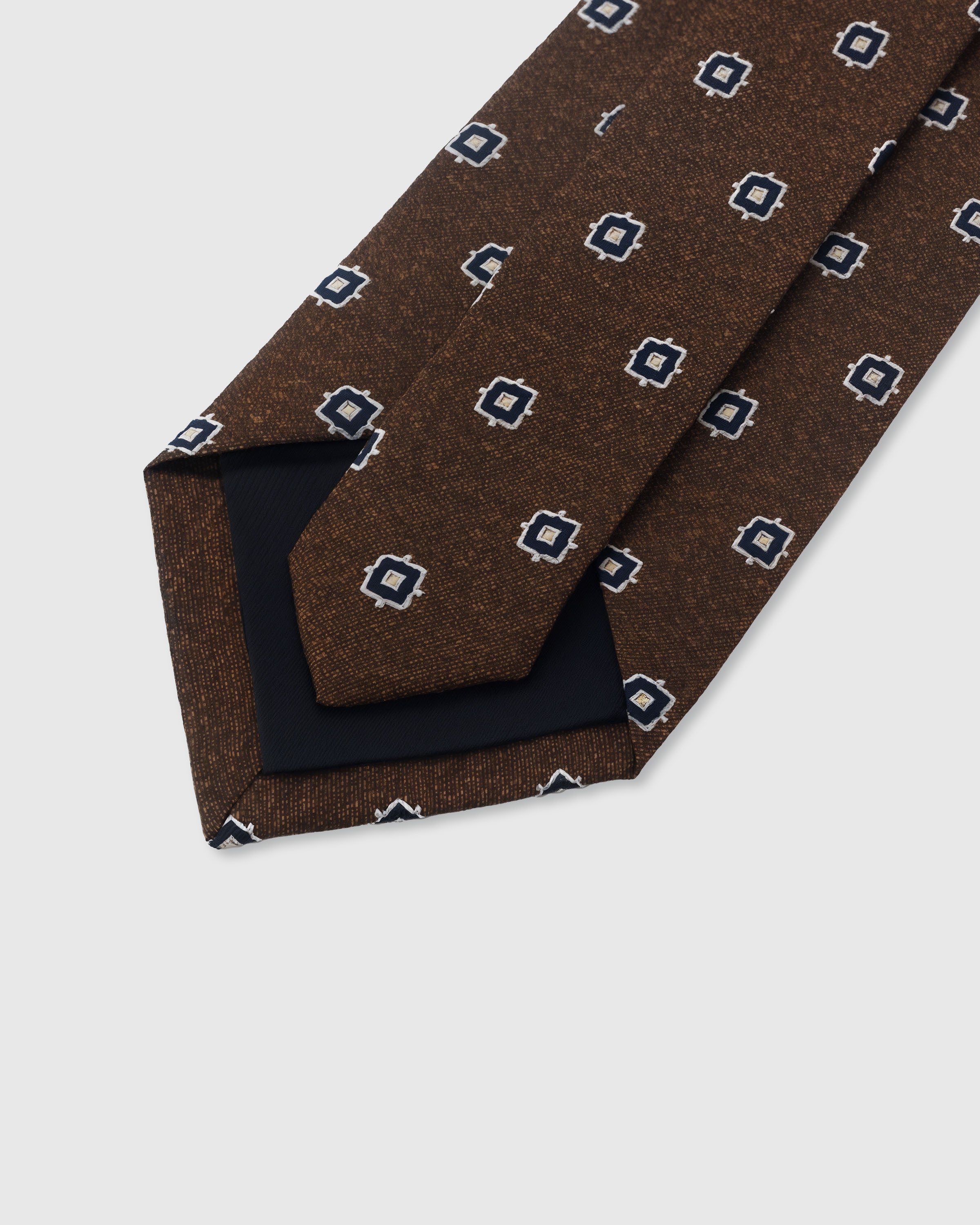 {Hand-finished interior} STICKYZOO UMBER NAVY FOULARD TIE back detail showing structured interlining and hand-finished slip stitching, 145 x 8 cm