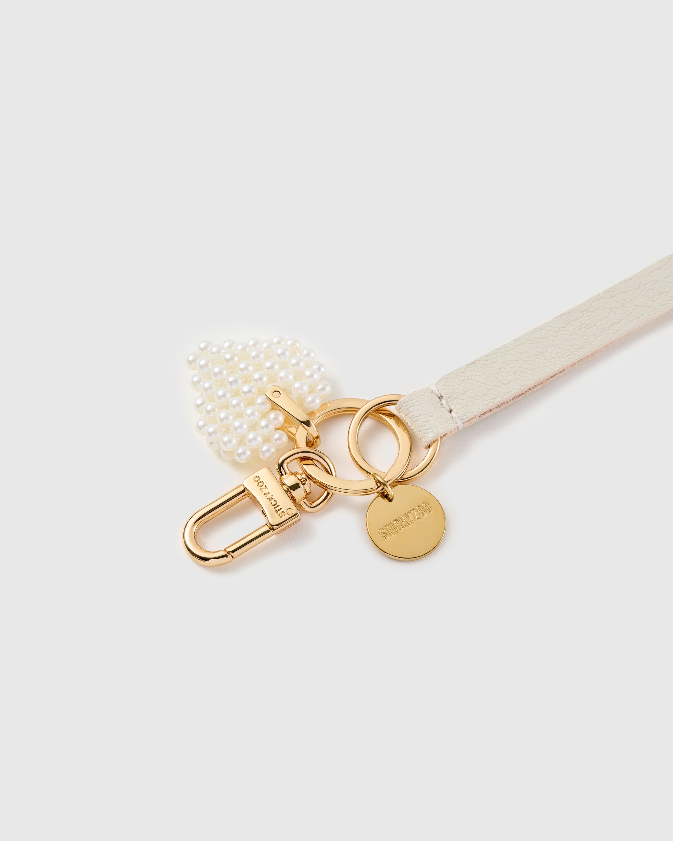 Mini pearl heart leather phone strap clipped to a phone case showing the hands-free wrist loop in use