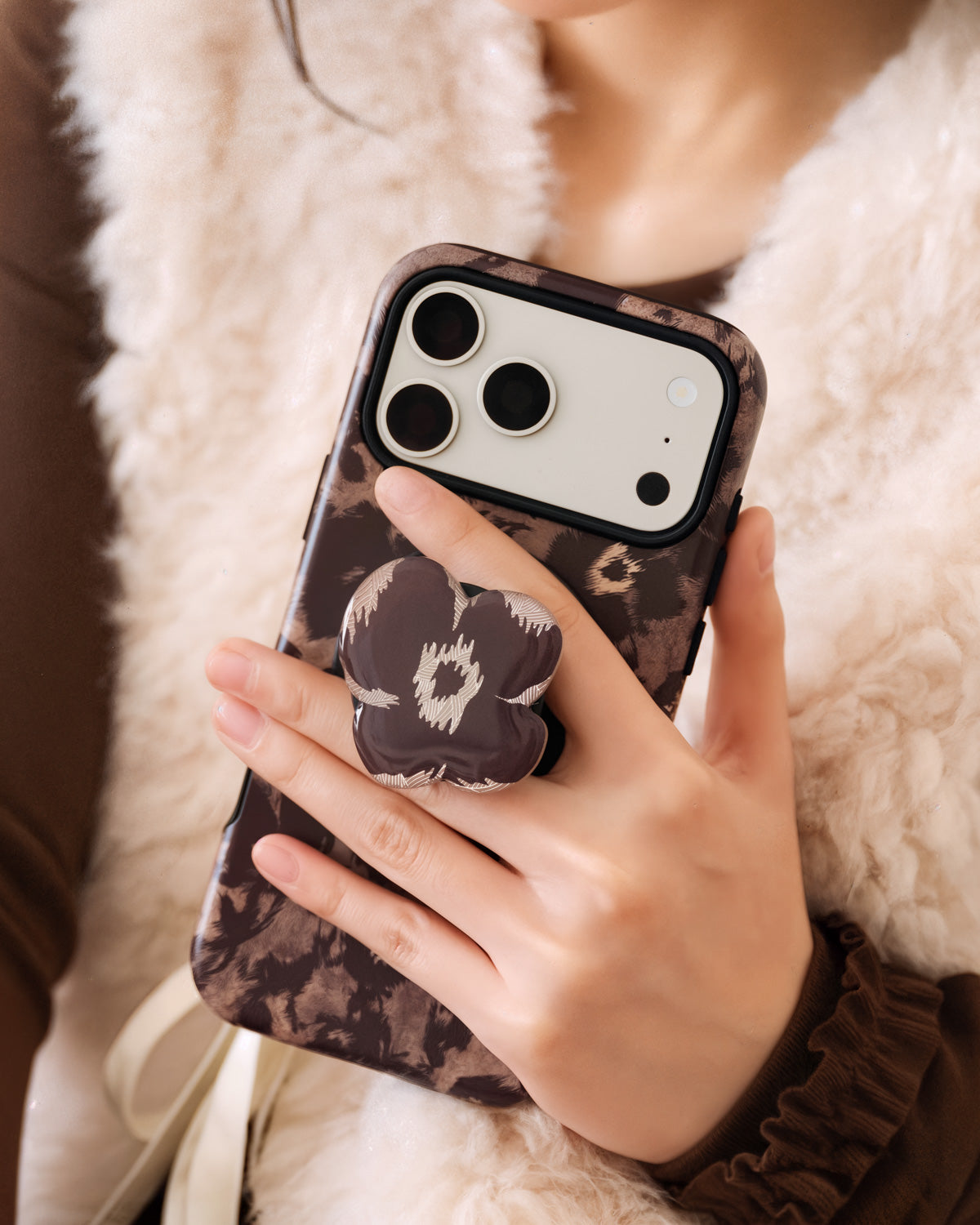 STICKYZOO burgundy poppy phone case held in hand with the retractable MagSafe grip extended