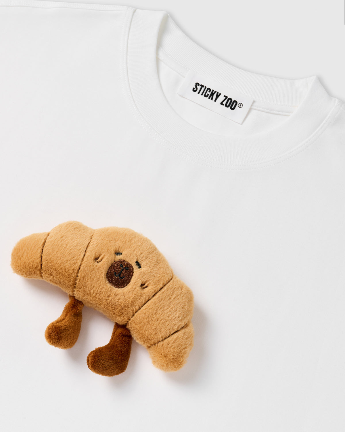 Detail of hand-stitched croissant applique on STICKYZOO white t-shirt showing dimensional craft