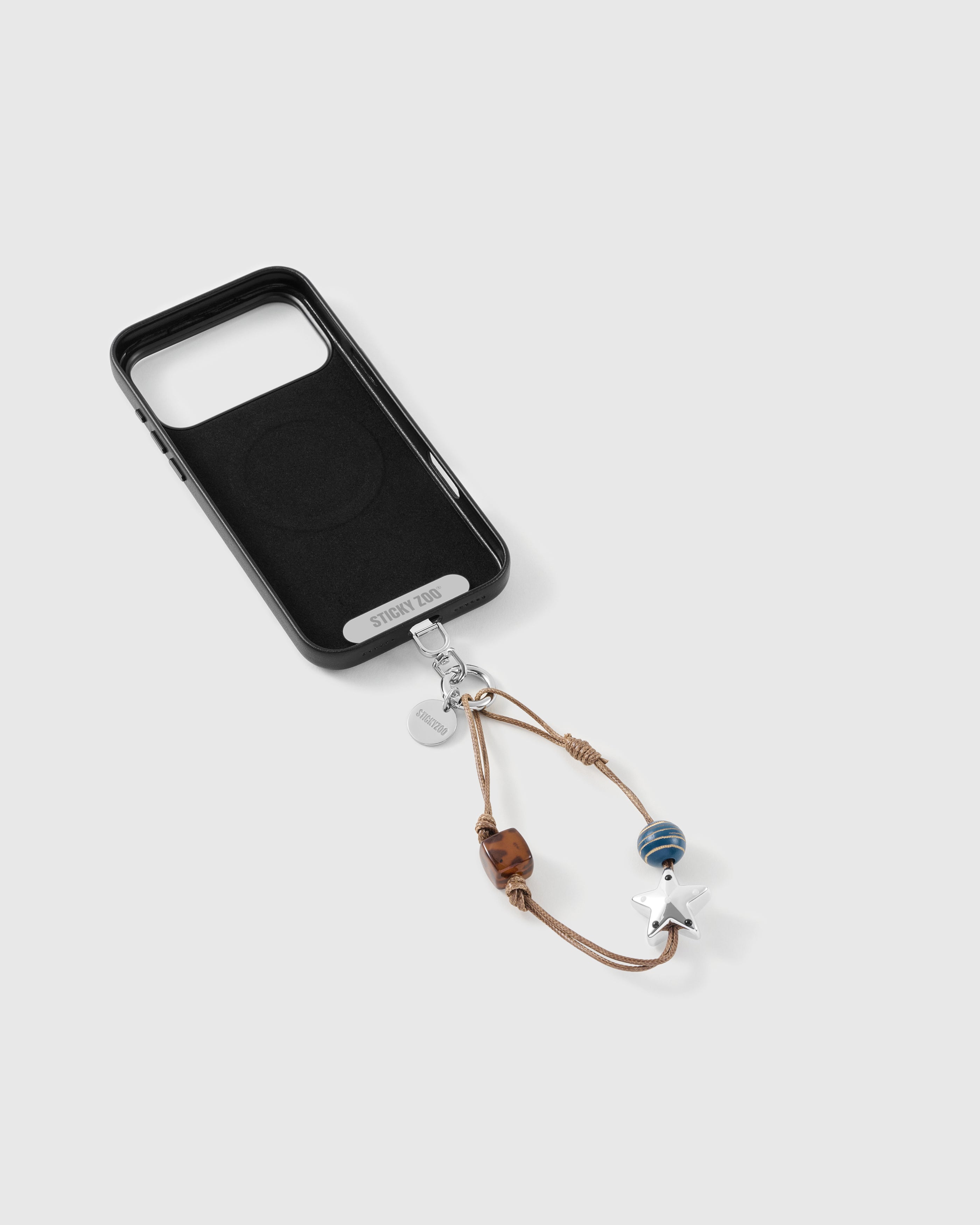 Beaded strap clipped to a black case, showing the silver-tone hook, engraved STICKYZOO disc and the tortoiseshell and star beads.