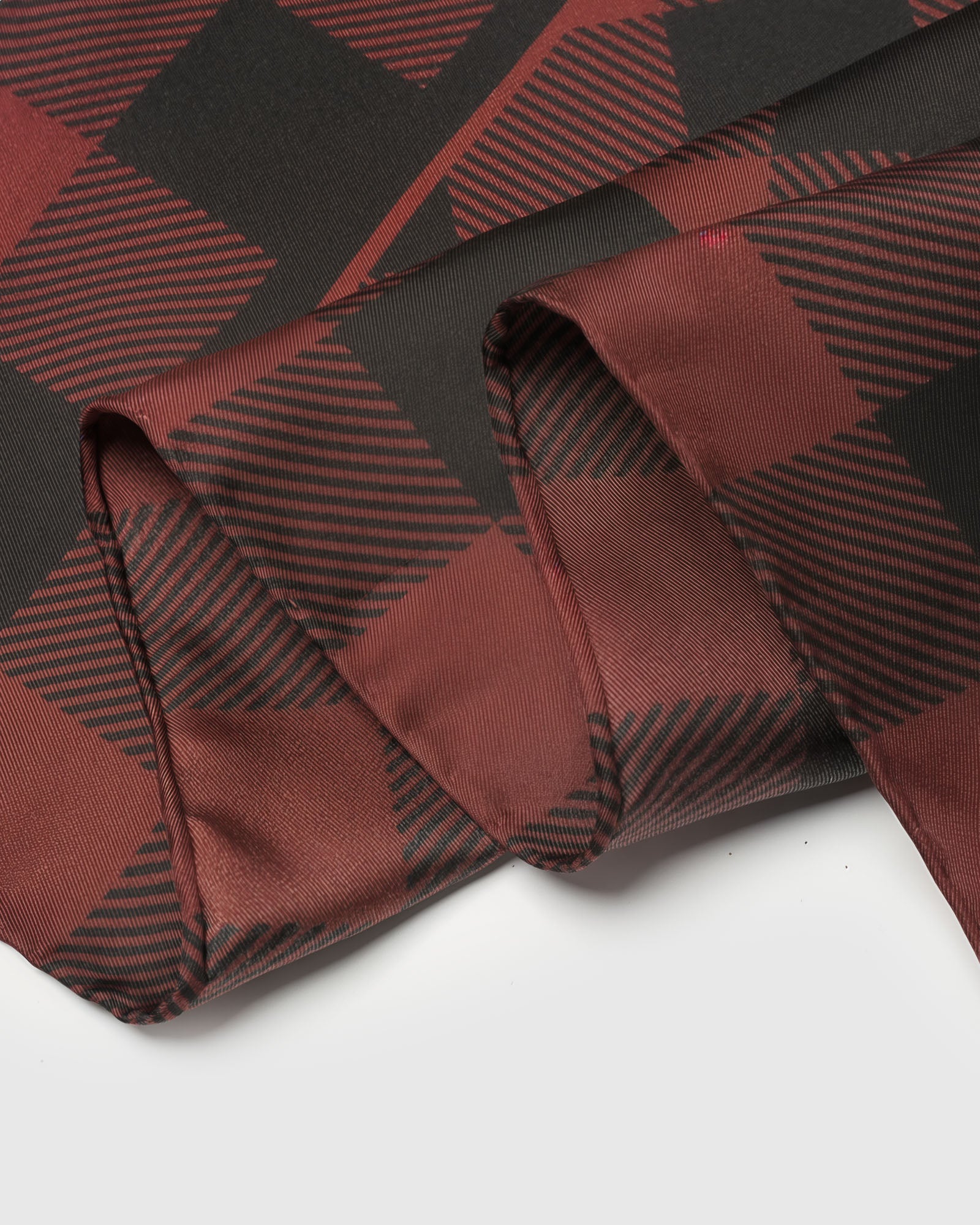 Edge detail of the buffalo check silk scarf showing the inner burgundy frame and silk hand