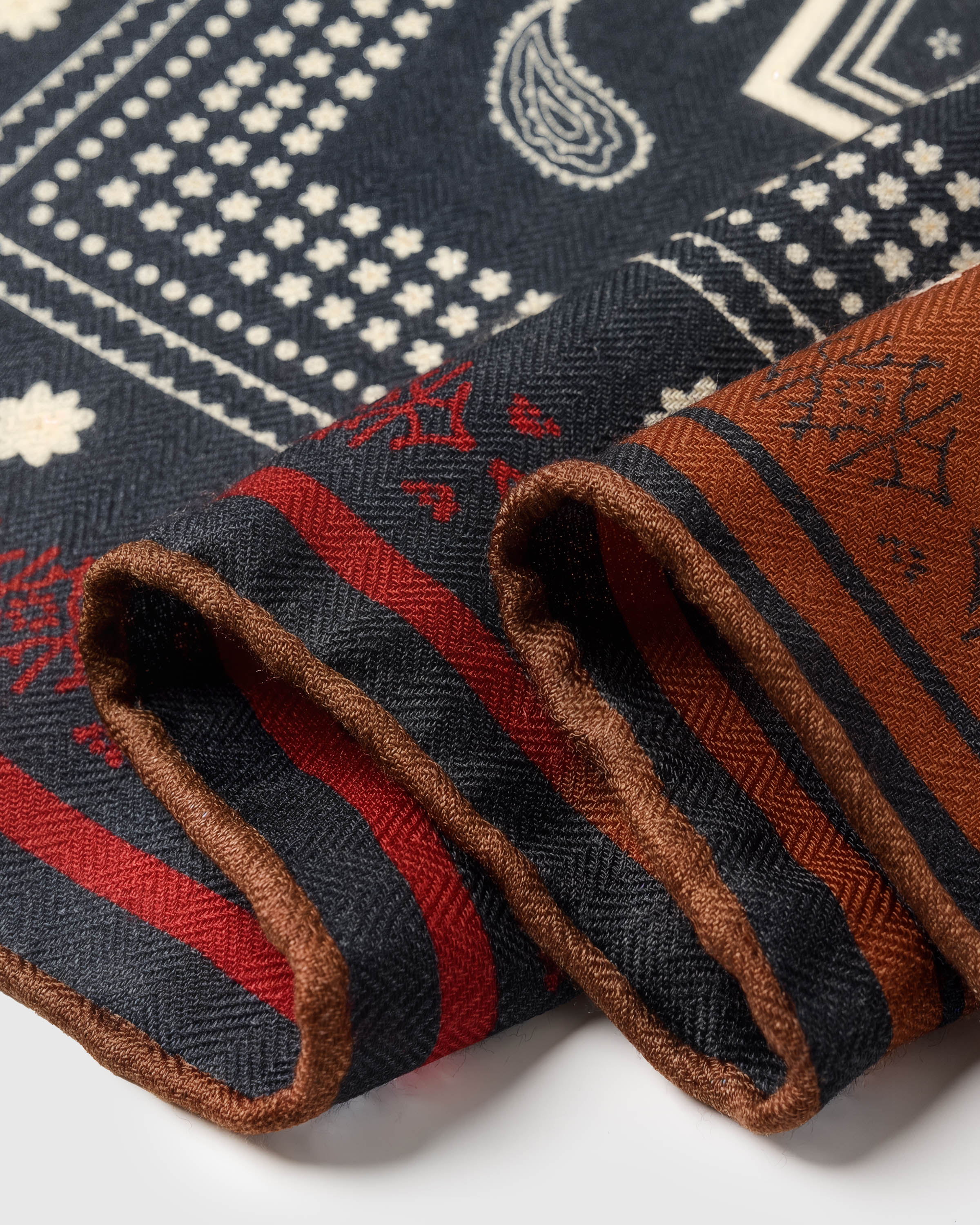 Edge detail of the saddle bandana silk scarf showing the red trim and rust border in pure silk