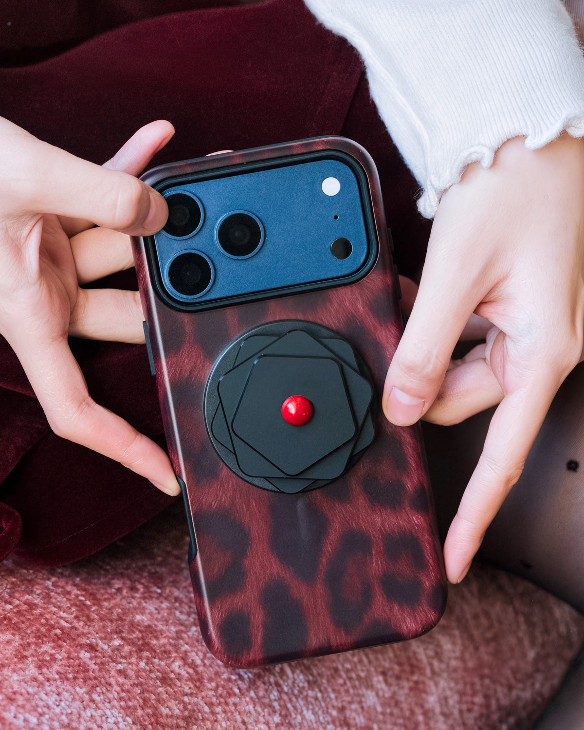 STICKYZOO iris aperture phone case held in both hands with the geometric MagSafe grip on the back