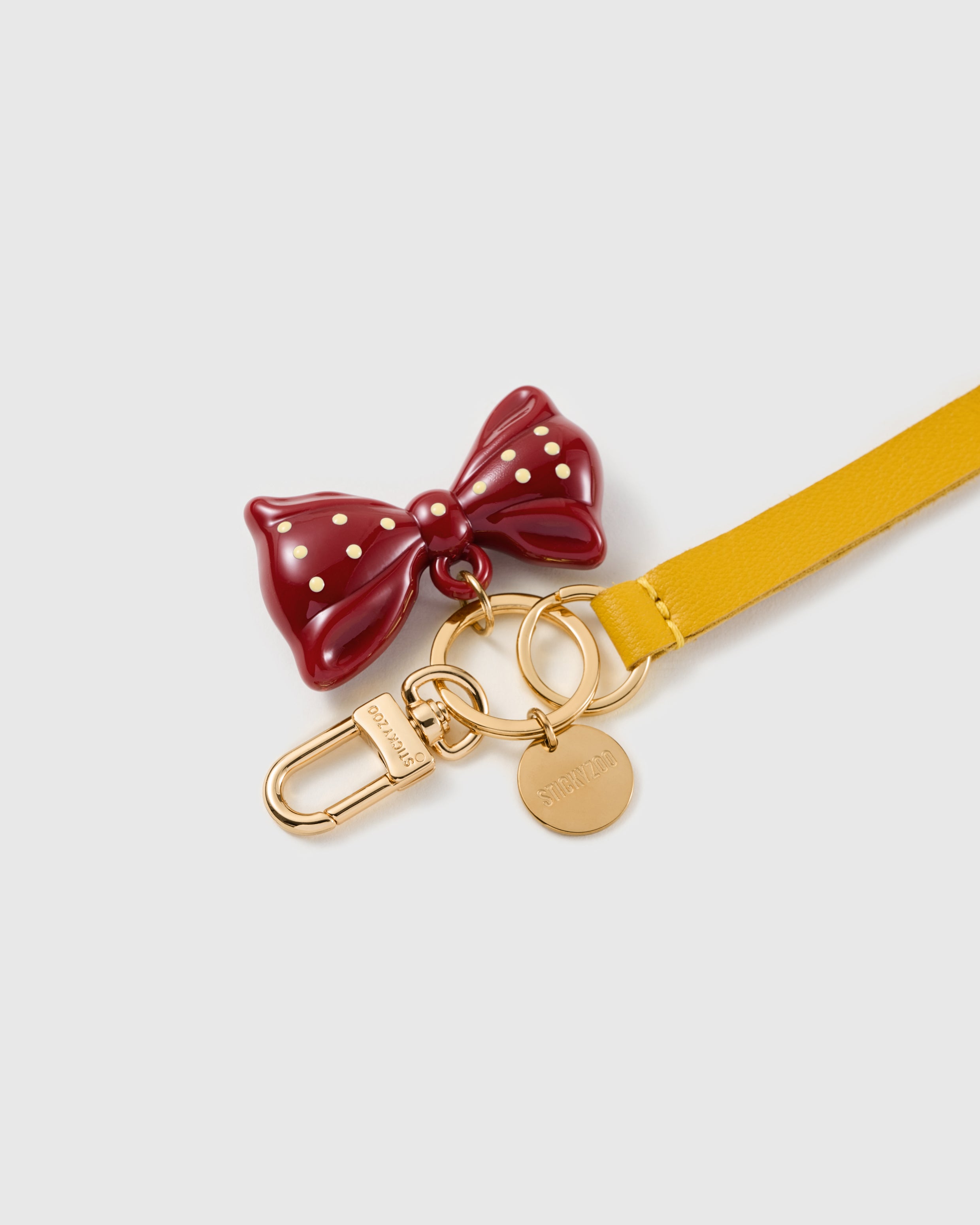 Polka bow leather phone strap clipped to a phone case showing the hands-free wrist loop in use