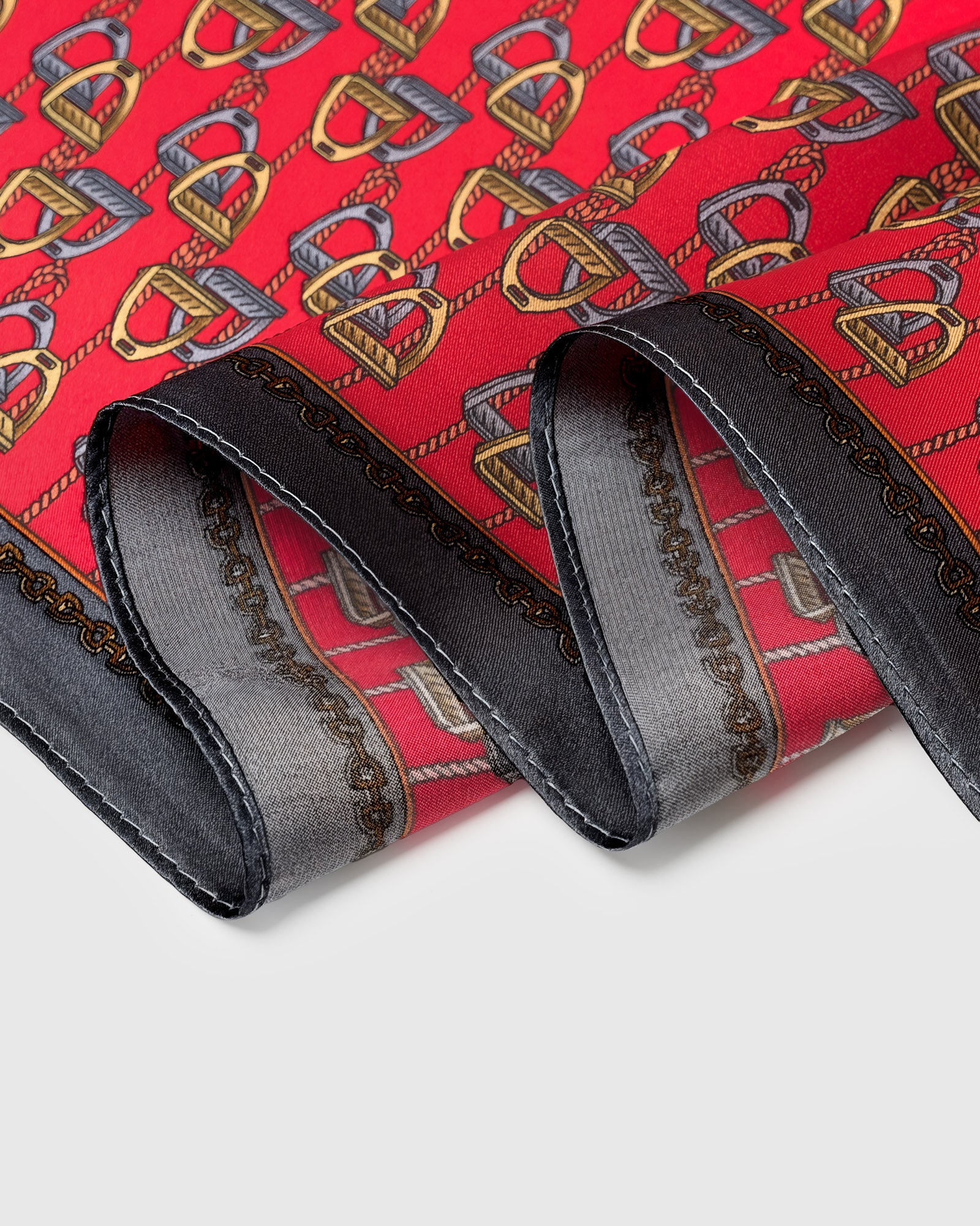 Close-up of the hand-illustrated stirrup motif and black chain border printed on pure silk