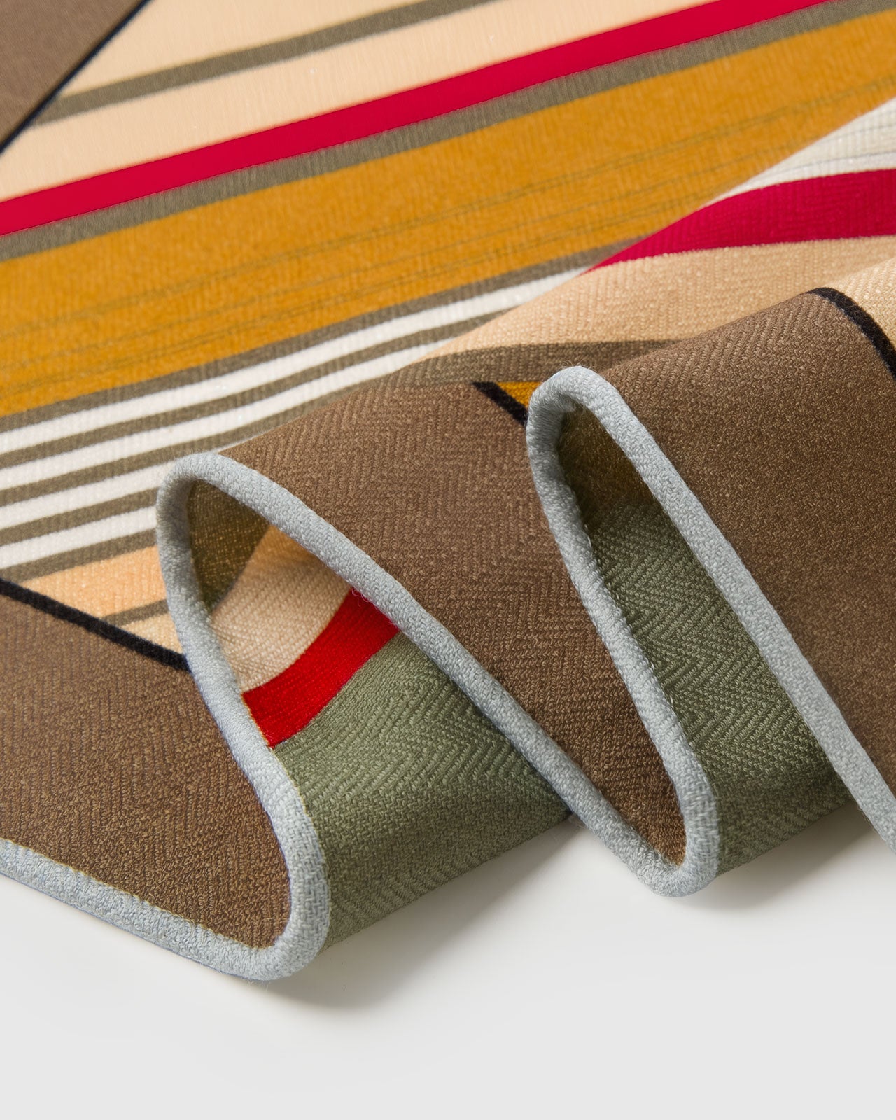 Close-up of the taupe silk scarf border meeting the mustard stripe print on pure silk
