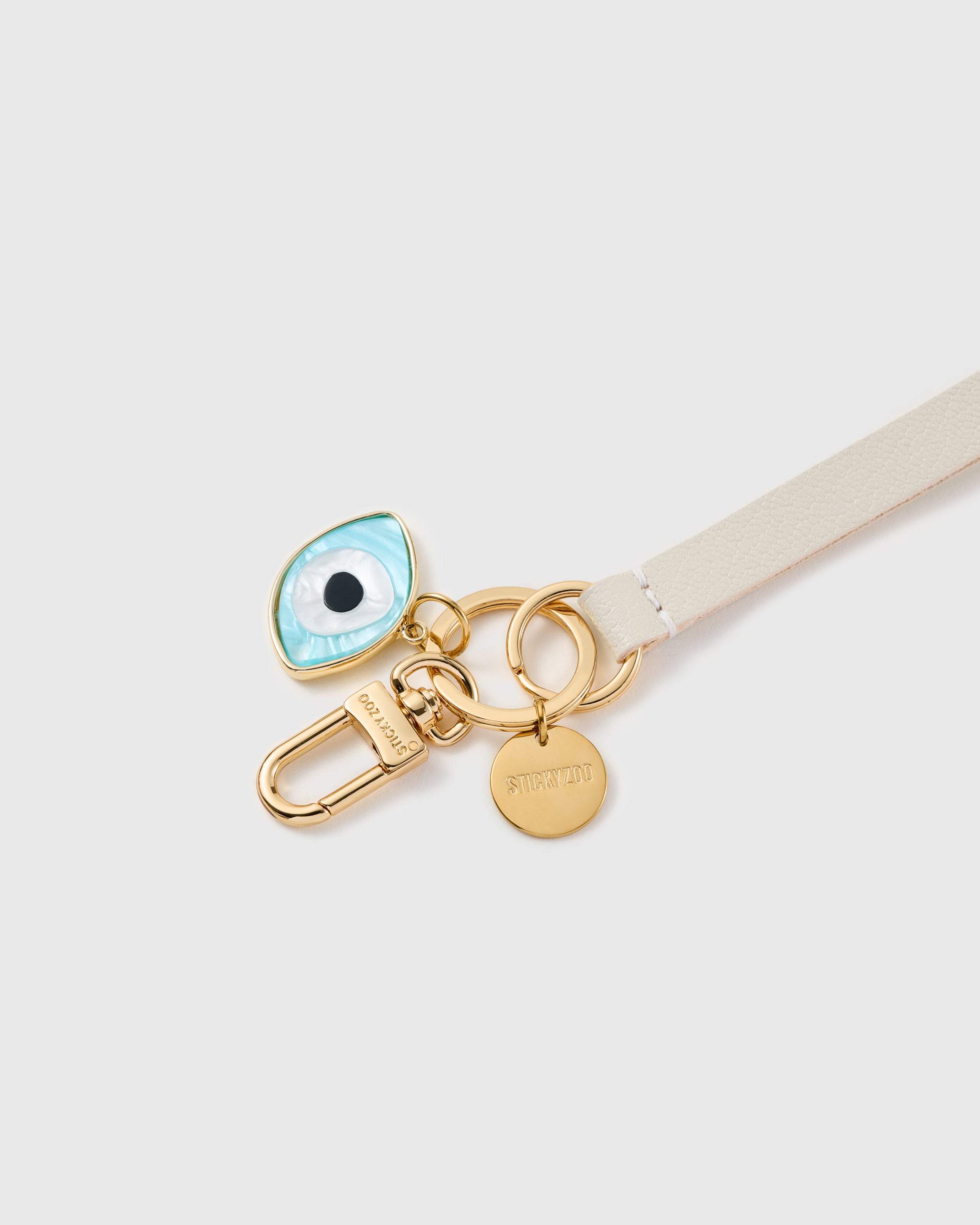 Evil eye cream leather phone strap clipped to a phone case showing the hands-free wrist loop in use