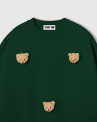 Close-up of hand-stitched plush teddy bear face with golden textured fur and embroidered features on green cotton