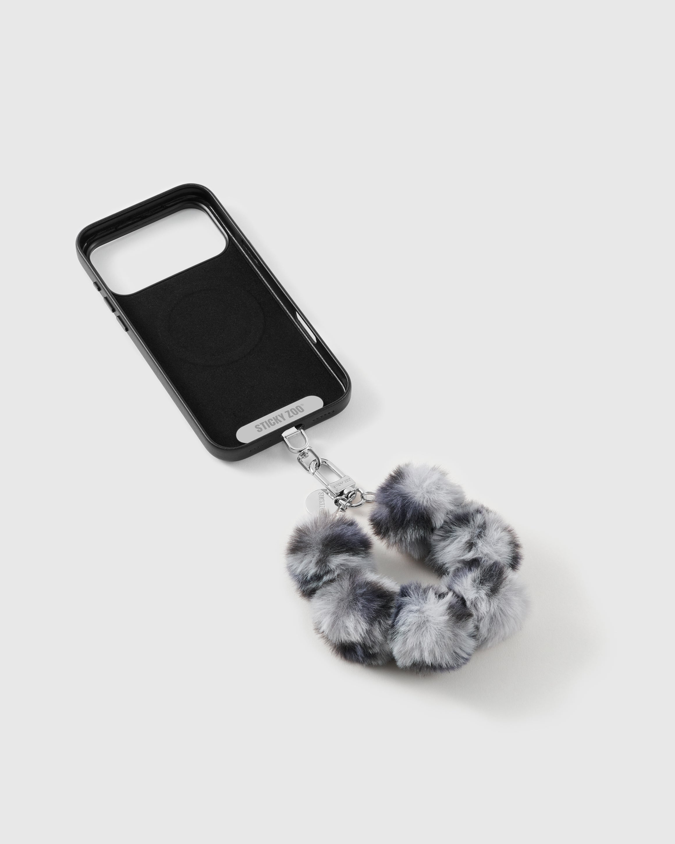 Smoke Pom phone strap by STICKYZOO on a black case, ready for everyday hands-free carry