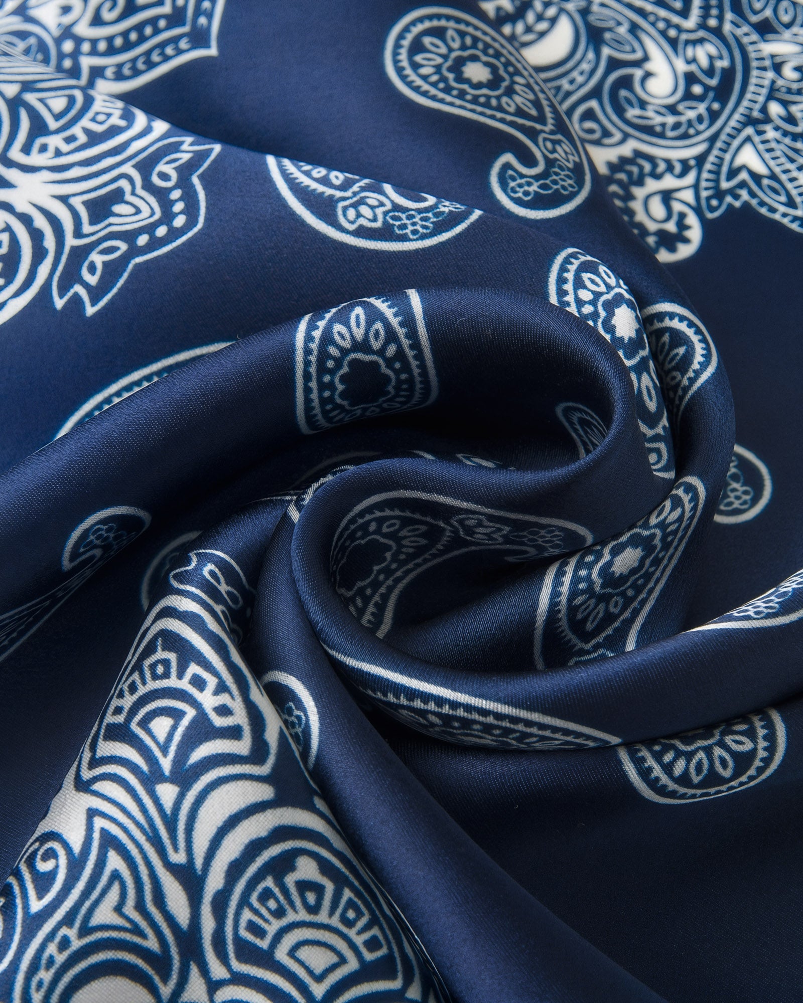 Close-up of the navy silk swirled to show the ivory paisley boteh and the soft drape