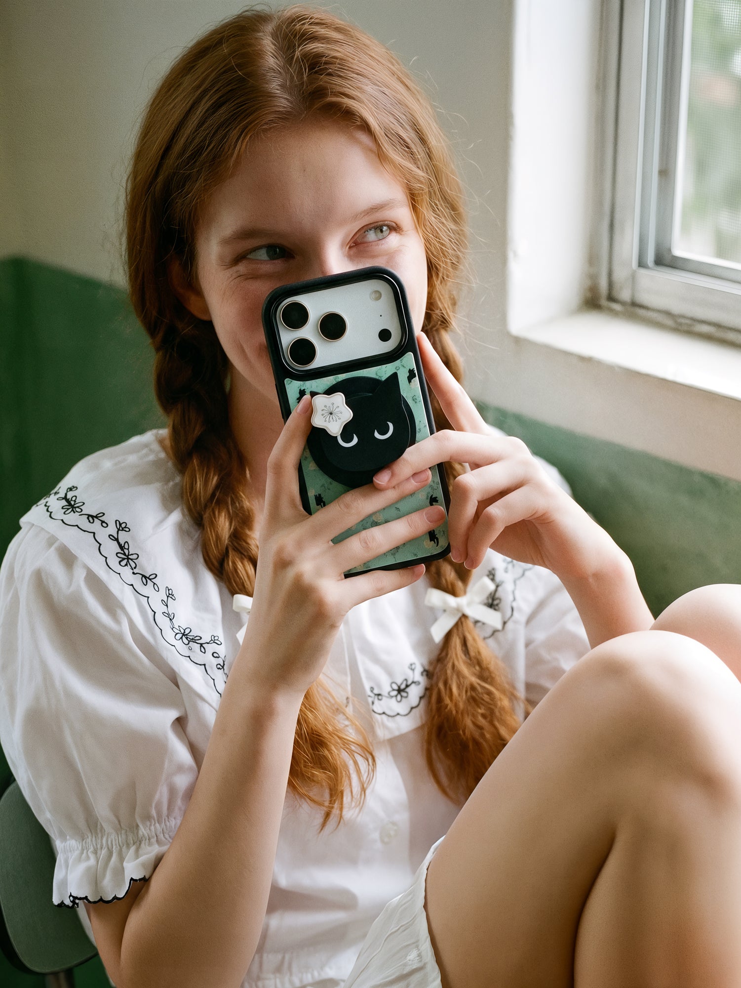 STICKYZOO midnight cat phone case held in everyday use, with the cat-face grip and mint floral print facing out
