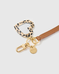 Leopard heart mirror leather phone strap clipped to a phone case showing the hands-free wrist loop in use