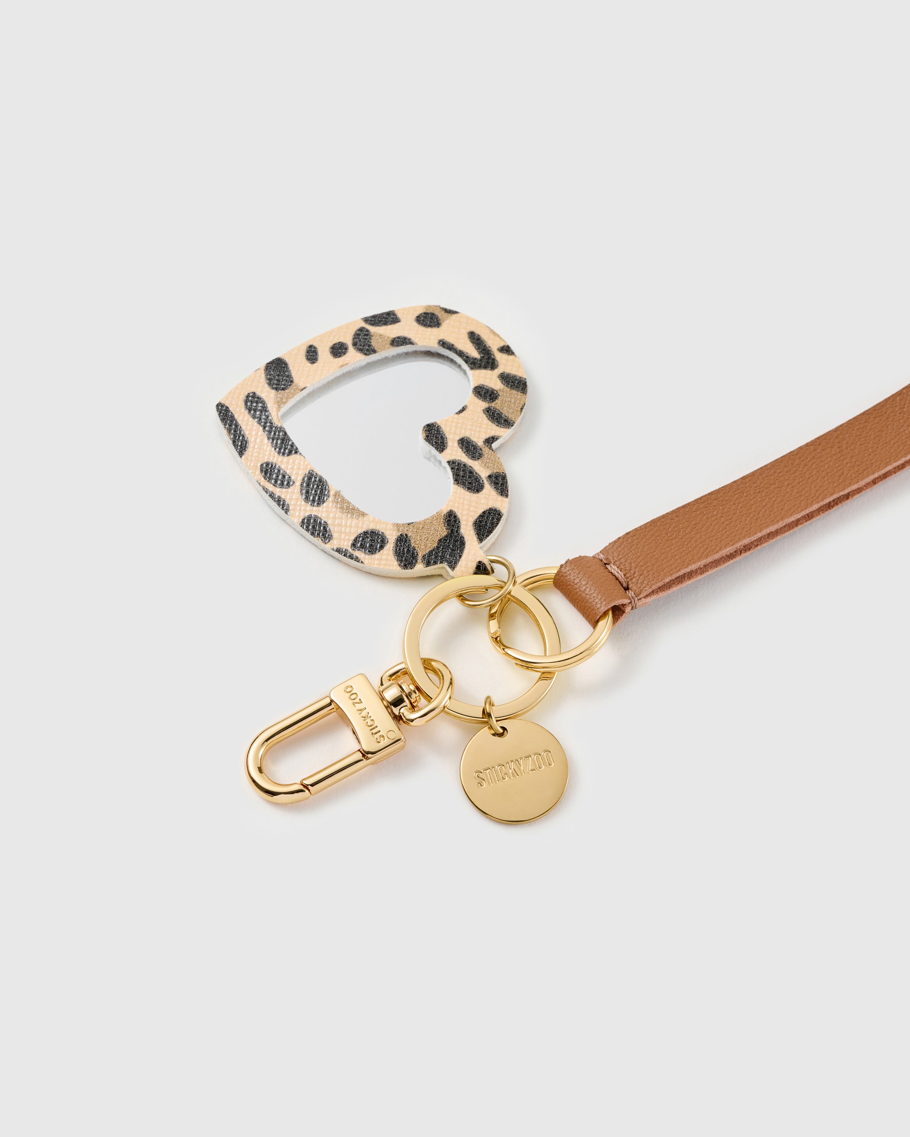 Leopard heart mirror leather phone strap clipped to a phone case showing the hands-free wrist loop in use