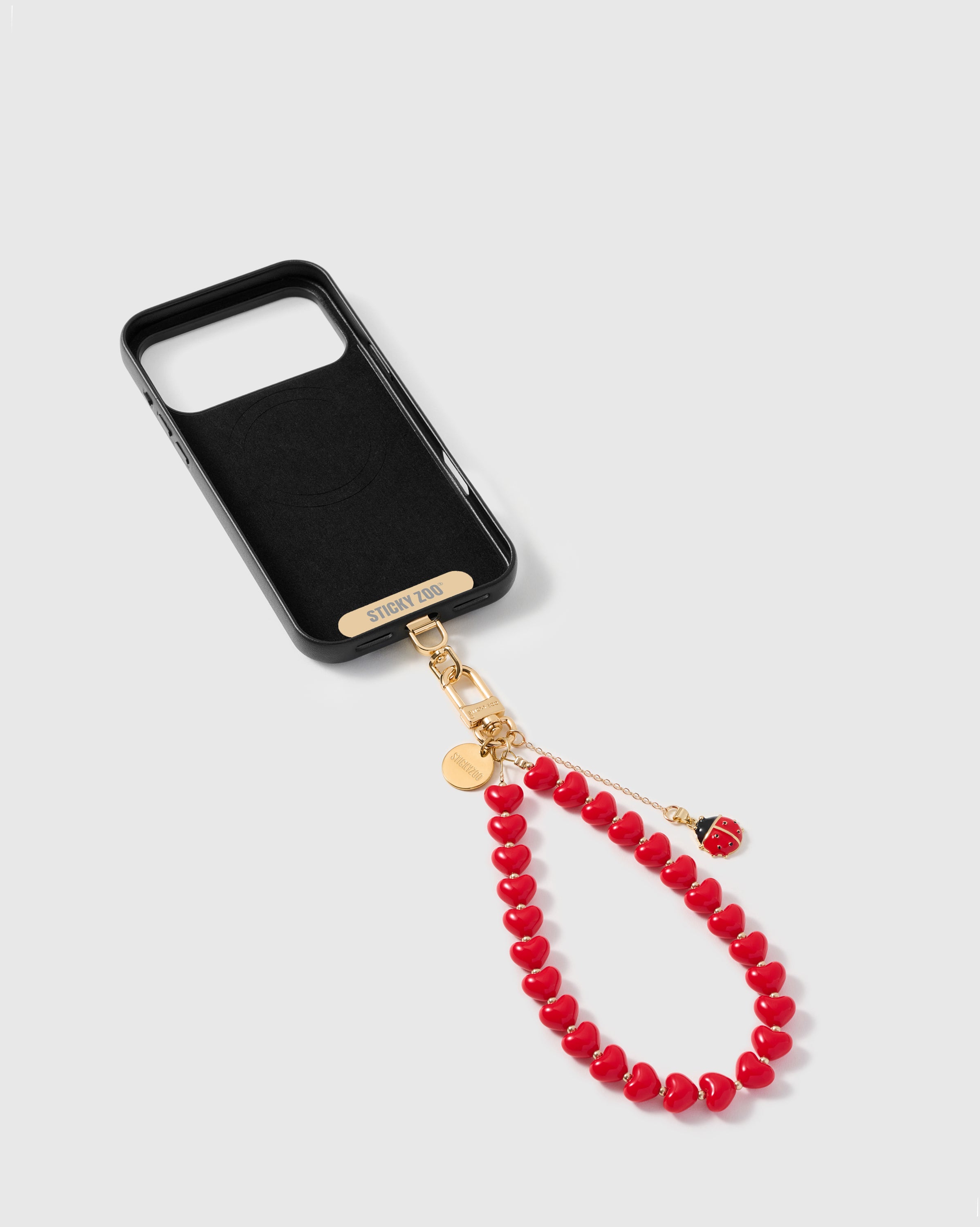 Inside phone case showing STICKYZOO Phone Strap Card paired with the lucky ladybug strap