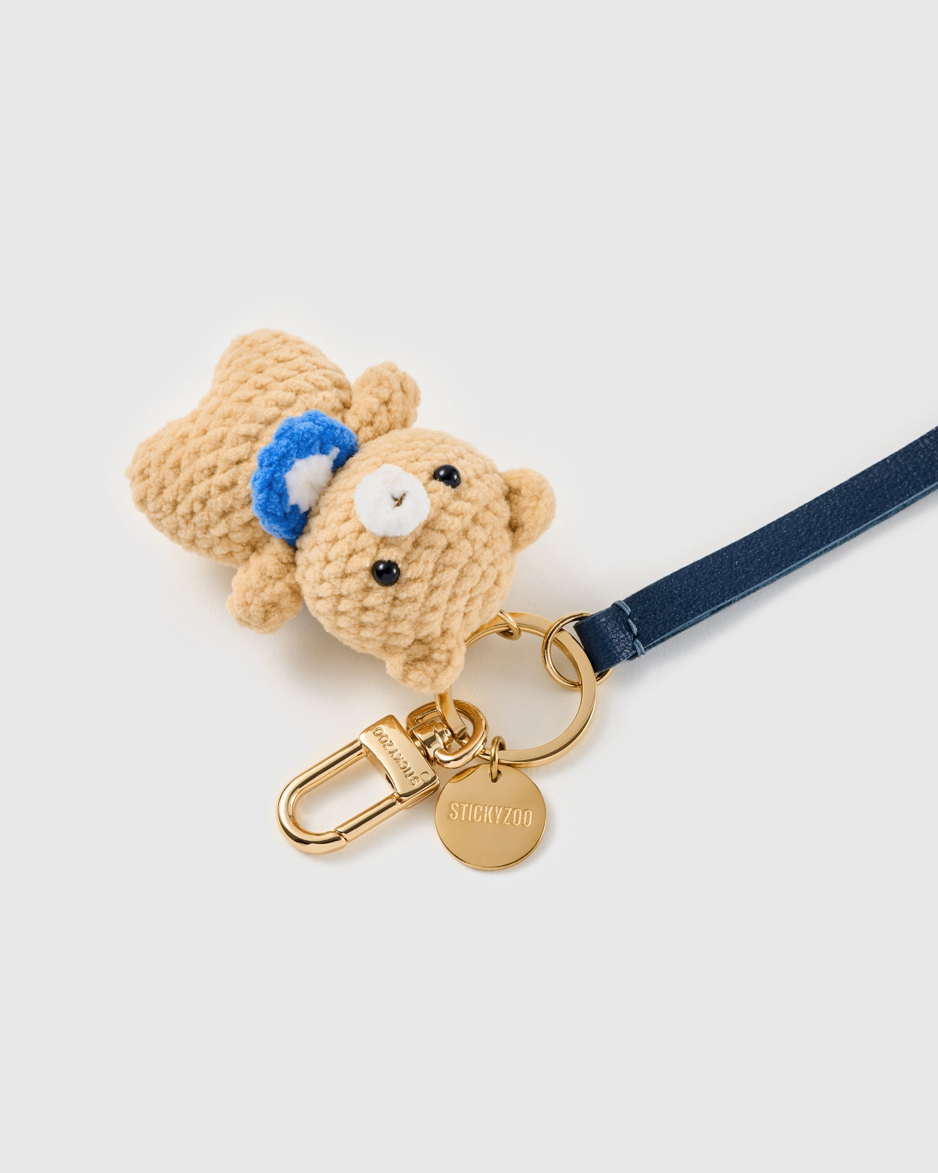 Tiny teddy leather phone strap clipped to a phone case showing the hands-free wrist loop in use
