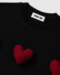 Model wearing STICKYZOO Triple Heart T-Shirt in black showing heart placement and dropped shoulders