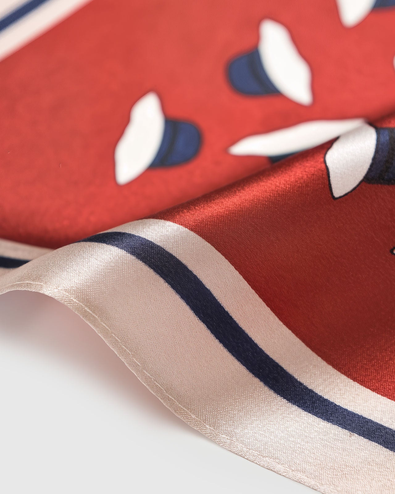 Close-up of the silk scarf border showing the rust frame, navy stripe, and blush piping meeting the silk field