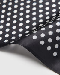 Close-up of the hand-illustrated ivory polka dots printed in archival inks on pure black silk
```