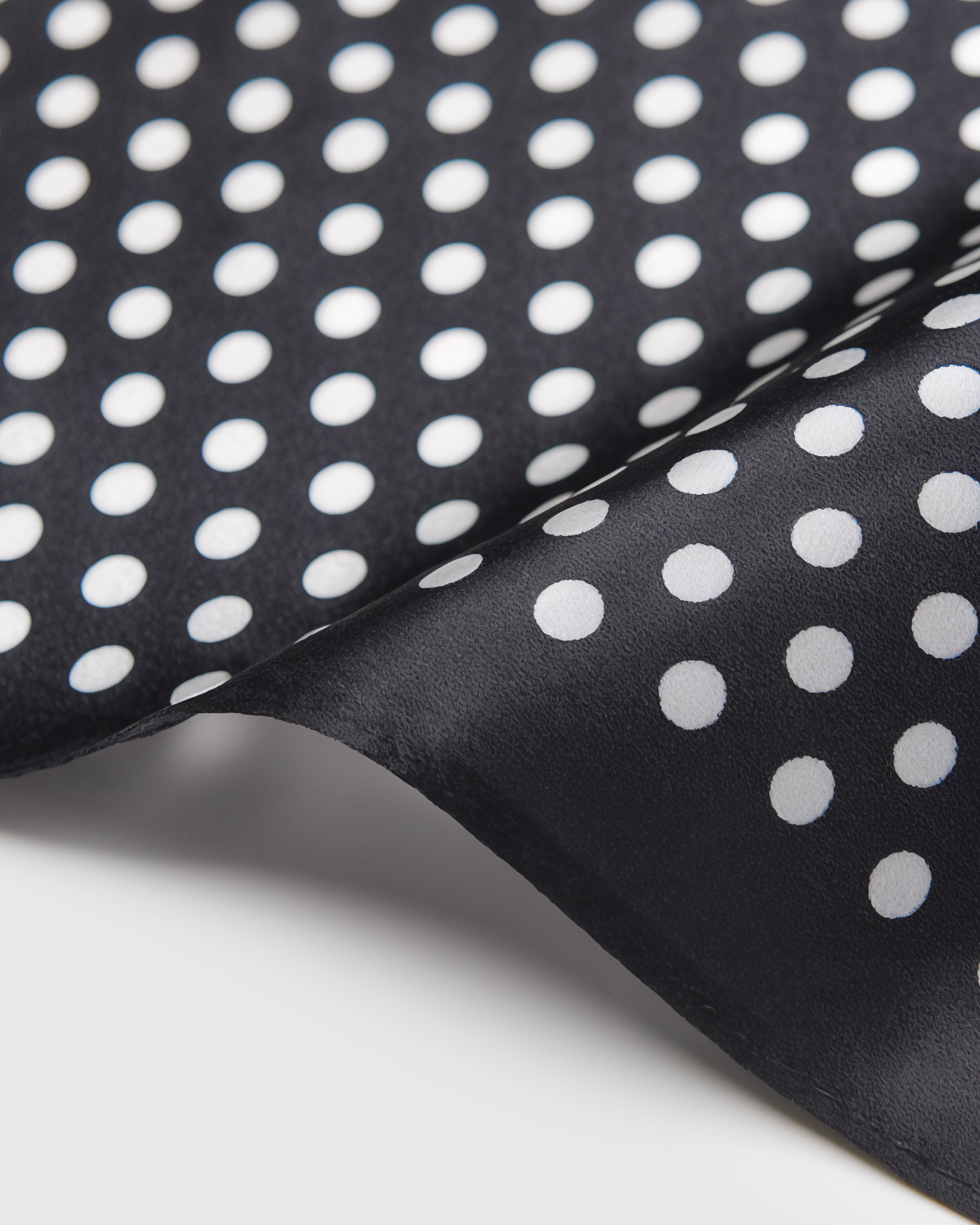 Close-up of the hand-illustrated ivory polka dots printed in archival inks on pure black silk
```