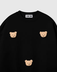 Detail of scattered bear face appliques on STICKYZOO black sweatshirt showing handmade craft