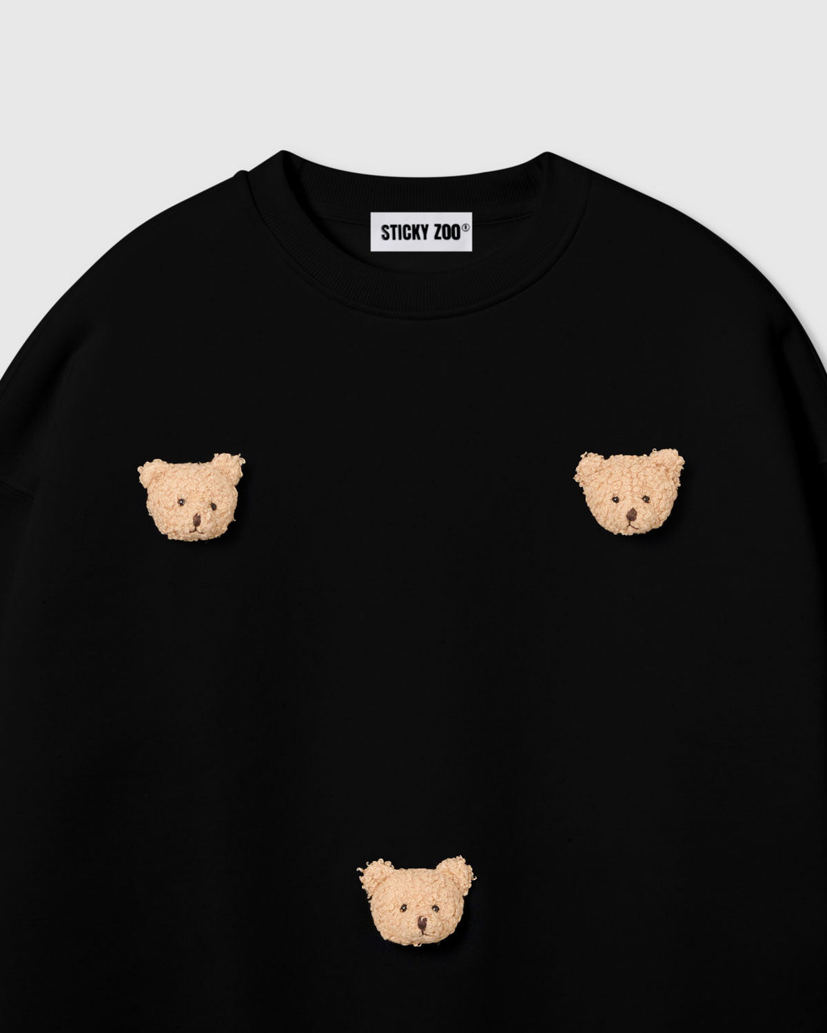 {{Rated 4.9 by thousands}} Detail of scattered bear face appliques on STICKYZOO black sweatshirt showing handmade craft