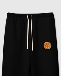Close-up of golden plush croissant with smiley face on black cotton showing maximum contrast and layered depth