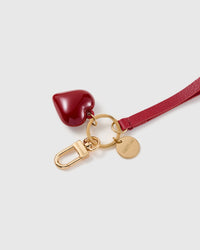 Ruby heart leather phone strap clipped to a phone case showing the hands-free wrist loop in use