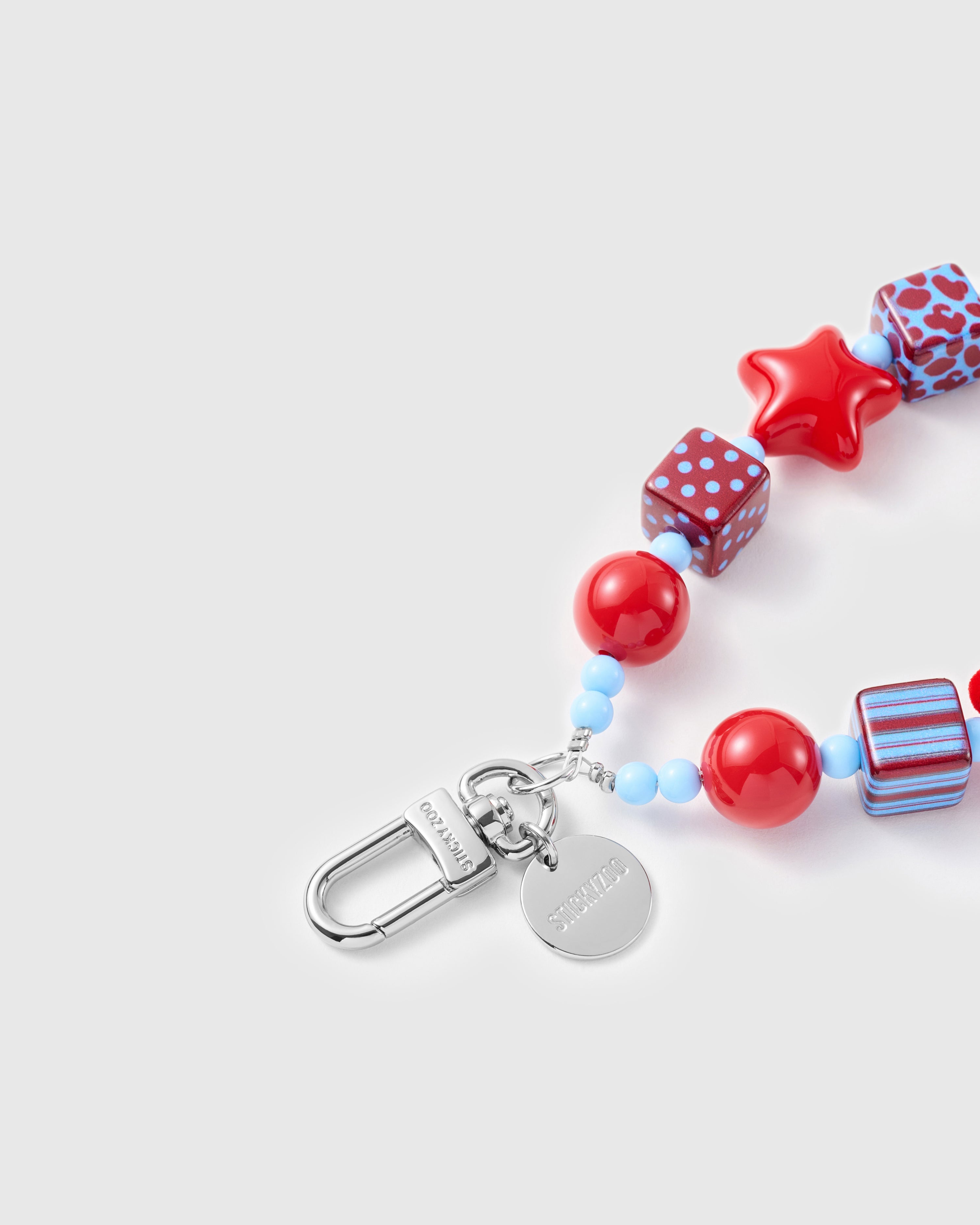 Crimson bear phone strap clipped to a phone case showing the hands-free wrist loop in use