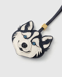 Close-up of husky charm showing hand-cut leather layers, embroidered blue eyes, and pebbled goatskin texture