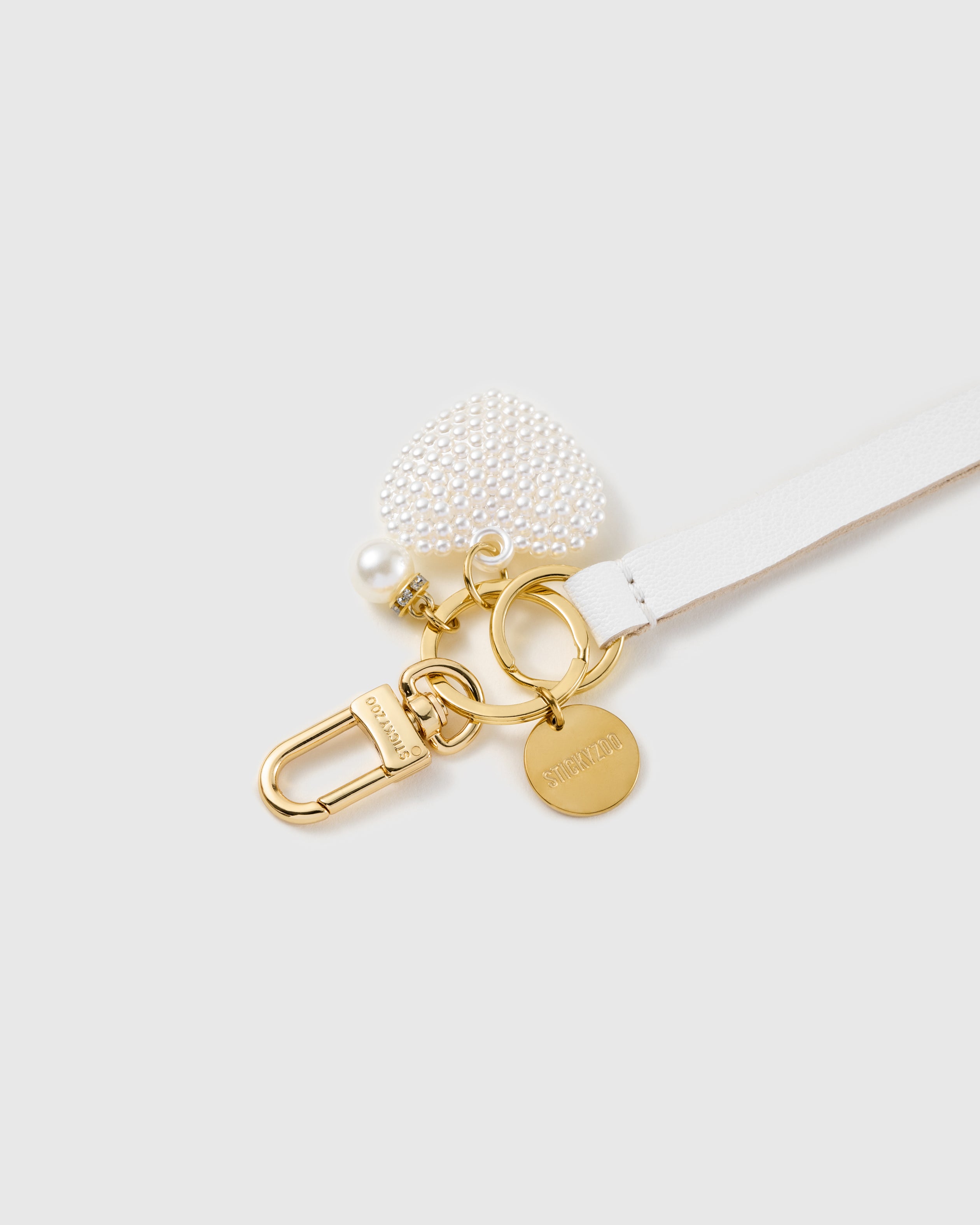 Pearl heart leather phone strap clipped to a phone case showing the hands-free wrist loop in use
