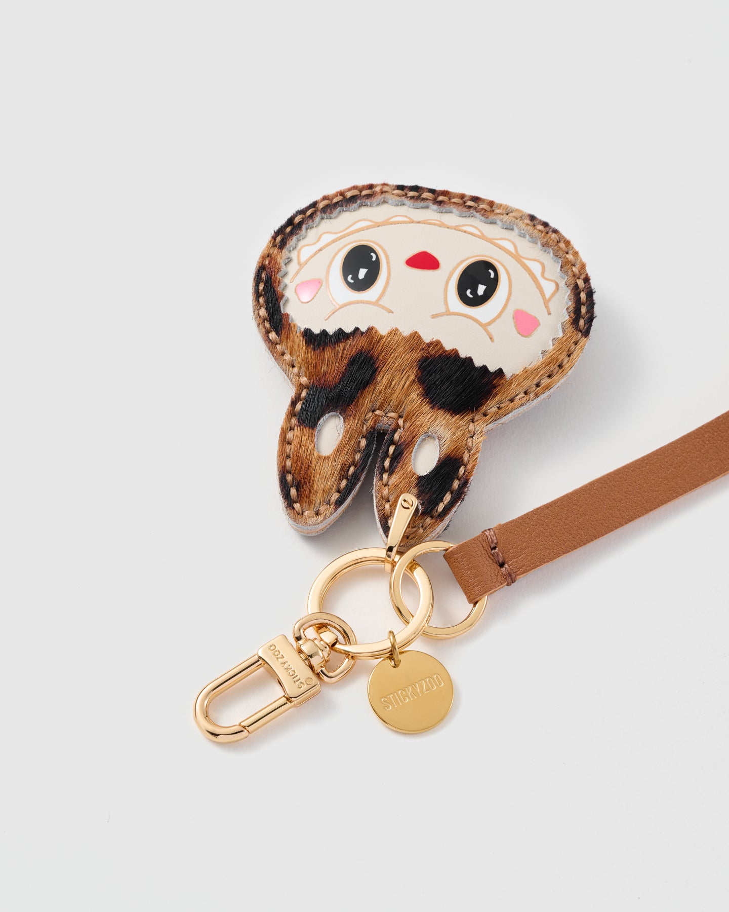 Close-up of the STICKYZOO leopard calf-hair critter charm, hand whip-stitched edge and hand-cut cognac leather