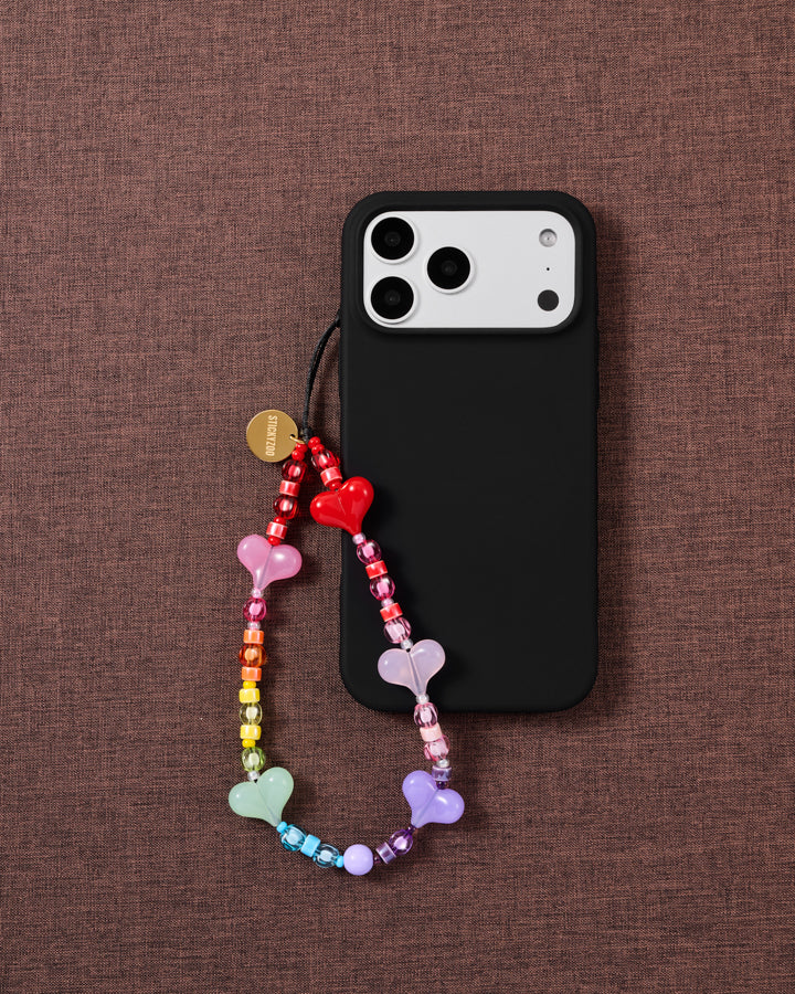 STICKYZOO rainbow jelly heart bead strap looped onto a black phone case on maroon fabric, hearts in red, pink, mint and lavender.