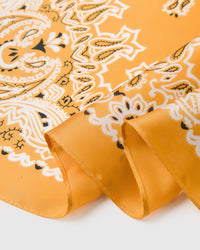 Close-up of the hand-illustrated paisley bandana corners printed in archival ivory and black on saffron silk