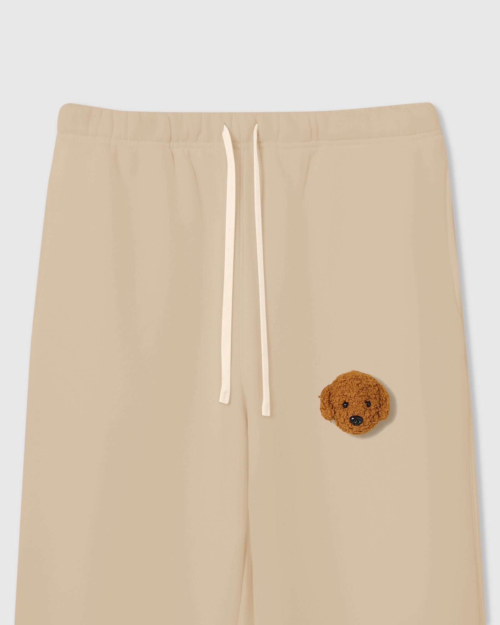 {{Not printed — stitched}} Close-up of plush poodle face applique on beige cotton showing curly dimensional texture