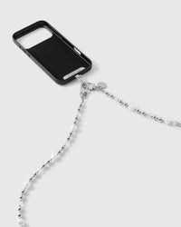 Back of a black-cased phone with the strap attached at a silver-tone dual clasp and round disc tag, beaded strand trailing down.