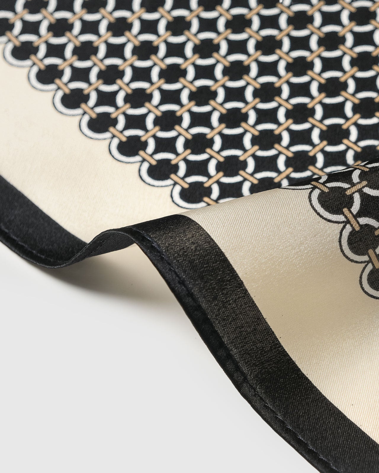 STICKYZOO chain link grid silk scarf swirled to show the soft drape and ivory-on-black graphic motif